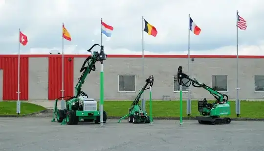 Picture of 3 green sleeved screw piles and the associacted driving equipment