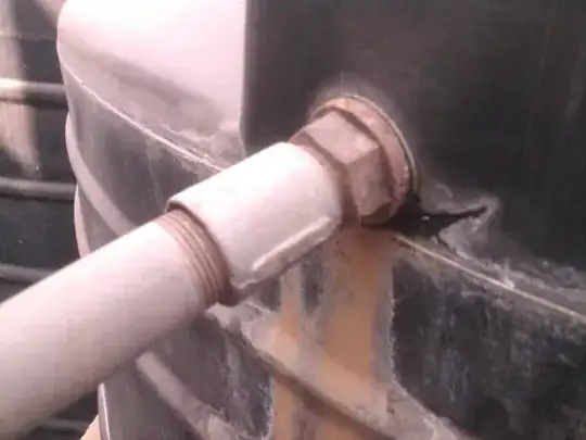 A closeup of the cracks in the tank areound the pipe.