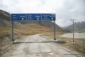 Road signs on Karakoram Highway near the Pakistan-China border featuring Pakistani destination names in Latin, Chinese, and Cyrillic script