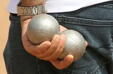 Two boules being held in one hand behind the Pétanque player's back.